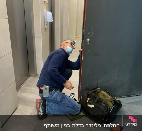 אדם עובד על דלת עם כלים לתיקון מנעולים
